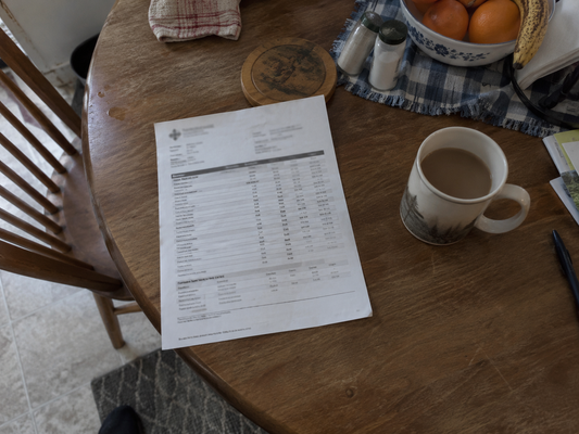 A blood panel printout on a kitchen table beside a cup of coffee