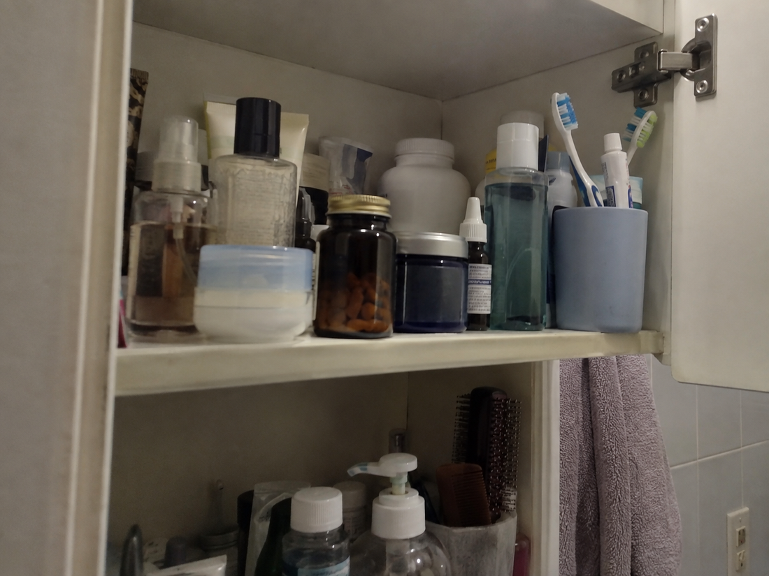 A bathroom cabinet shelf holding several supplement bottles