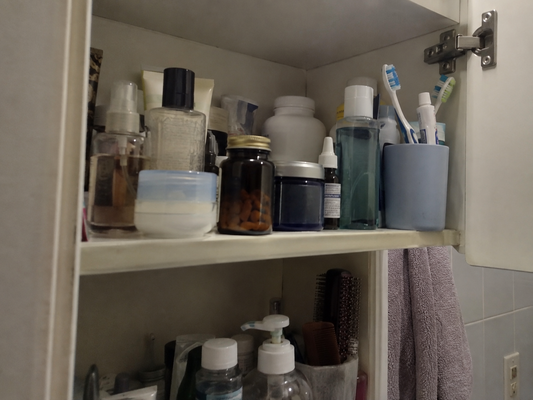 A bathroom cabinet shelf holding several supplement bottles